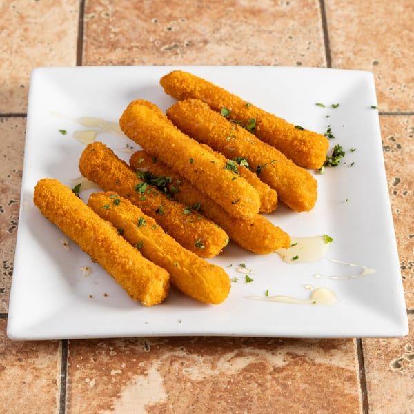 A white rectangular plate holds several golden-brown mozzarella sticks drizzled with sauce and parsley.